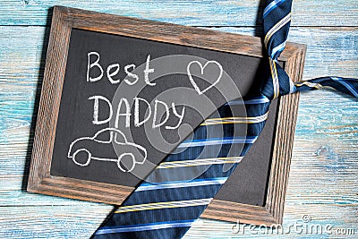 Fathers day concept, Best Daddy and car written on chalkboard with blue striped tie on wooden background Stock Photo