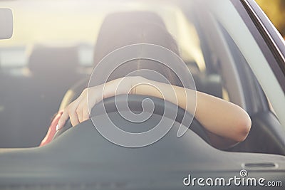 Fatigue sleepless female driver leans on wheel, stops to have rest, poses in car, covered long distance during night, feels tired. Stock Photo