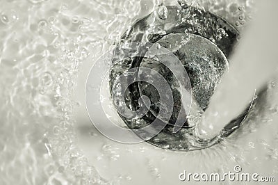 Faucet running on bathroom chrome drain stopper with water and bubbles Stock Photo