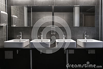 Faucets with washbasin in public restroom in grey colors Stock Photo