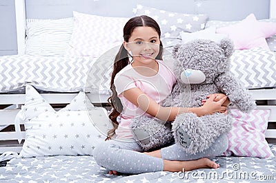 Favorite toy. Girl child sit on bed hug teddy bear in her bedroom. Kid prepare to go to bed. Pleasant time in cozy Stock Photo