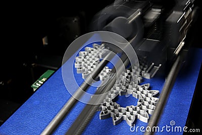 FDM 3D-printer manufacturing spur gears from silver-gray filament on blue print tape Stock Photo