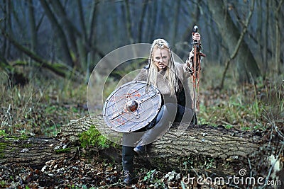 Viking woman warrior in forest with shield and sword in hand covered in blood. Stock Photo