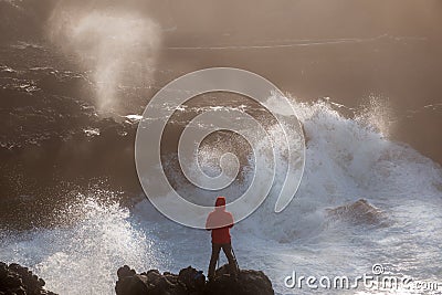 Fearless young photographer surrounded by raging waves at rocky Oregon coast Stock Photo