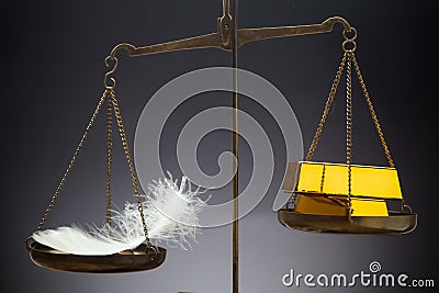 The feather outweighs a stacks of golden bars. Stock Photo