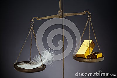 The feather outweighs a stacks of golden bars. Stock Photo