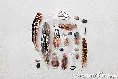 Feather pattern with pebble on gray stone background top view in flat lay style for boho theme. Stock Photo