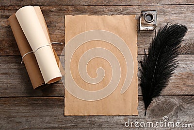 Feather pen, inkwell and blank parchment on wooden table, top view Stock Photo