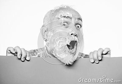 Feathers madness. Man bearded mature emotional face with stuck white feathers close up. Funny pensioner going crazy Stock Photo