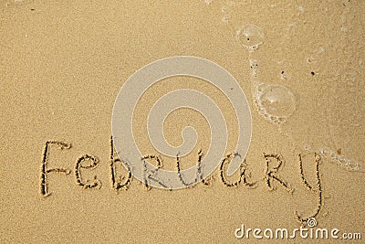 February - handwritten on the soft beach sand. Stock Photo