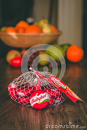 Babybel cheese on top of a wooden table with healthy fruit in the background Editorial Stock Photo