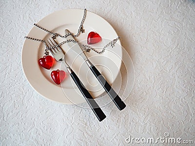 February 14 is Valentine`s Day, a holiday for all lovers. Still life of a white plate, knife, fork, three red hearts, two togethe Stock Photo