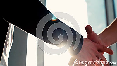 Fechamento de dois homens de negócios apertados de mão no fundo do sol Fechamento de dois homens de negócios apertados de mão no fundo do sol