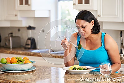 Fed Up Overweight Woman Eating Healthy Meal in Kitchen Stock Photo