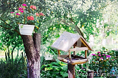 Feeder for birds in the garden near a flower pot. Summer sunny d Stock Photo