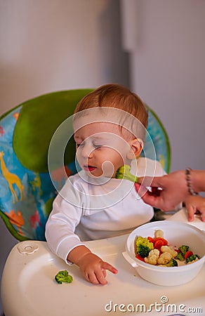 Feeding baby with vegetables -Beautiful baby refuses to eat broc Stock Photo