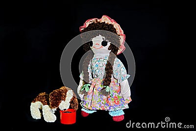 Here Puppy, time for your dinner. New pose. Vintage girl rag doll with her puppy; presented on a plain black background. Stock Photo