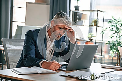 Feeling bad, tired, having headache, stressful. Senior businessman is working in the office Stock Photo