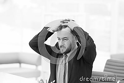 Feeling exhausted. Frustrated young beard man massaging his nose and keeping eyes closed while sitting at his working Stock Photo