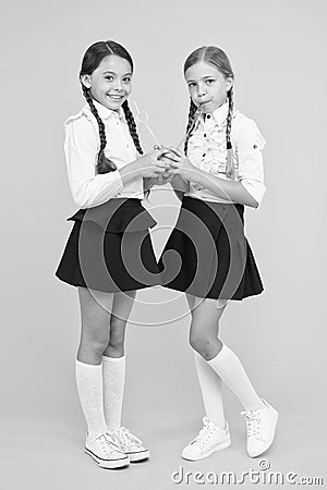 Feeling healthy is wonderful. Thirsty school girls on yellow background. Little girls drinking juice from orange fruits Stock Photo