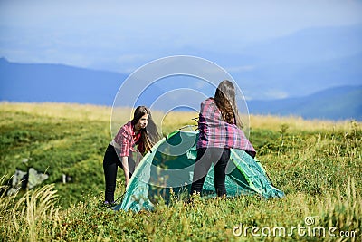 Feeling playful. friends spend free time together. family camping. reach destination place. two girls pitch tent Stock Photo