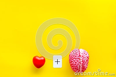 Feelings and mind concept with brain plus heart on yellow background top view mock up Stock Photo