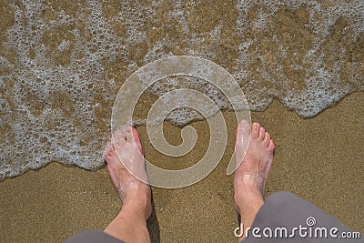 Feet of adult in water at beach Stock Photo