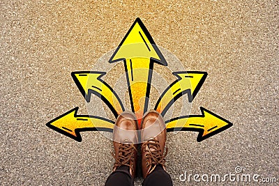 Feet and arrows on road background. Top view. Selfie woman in leather ankle boots on pathway with yellow graffiti arrow sign Stock Photo