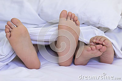 Feet in the Bed Sheets Stock Photo