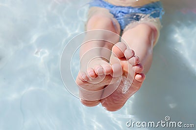 feet of a child - a boy lying in an inflatable children`s pool, in the water, swims on a warm day Stock Photo