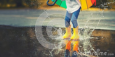 Feet of child in yellow rubber boots jumping over puddle in ra Stock Photo