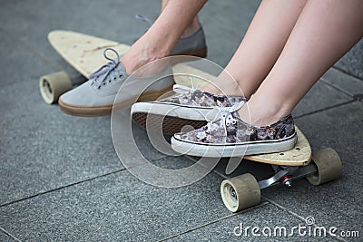 Feet couple of teenagers in sneakers on longboard Stock Photo