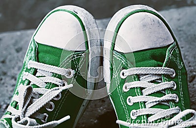 Feet in dirty green sneakers and jeans outdoors. Stock Photo