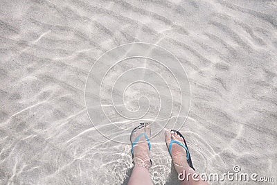 Feet in flip flops. Transparent sea water and white sandy bottom Stock Photo