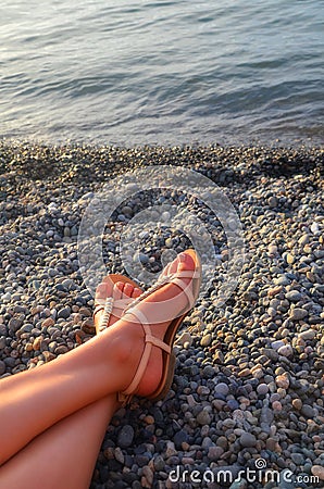 Feet girl sunbathing on a stony beach - vacation and travel concept Stock Photo