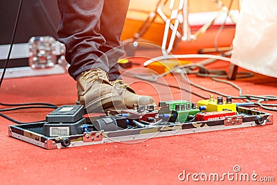 Feet of guitar player on a stage with set of distortion effect pedals. Stock Photo
