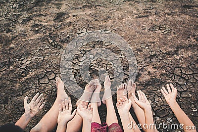 Feet and hand of children praying for the rain on cracked dry ground Stock Photo