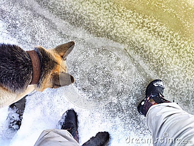 Feet of Hunter or fisherman in big warm boots And paws of dog on snow. Top view. Fisherman on ice of river, lake Stock Photo