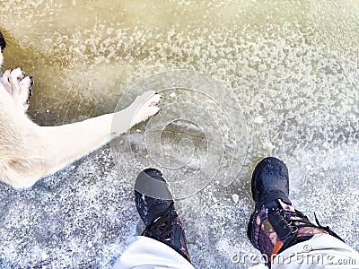 Feet of Hunter or fisherman in big warm boots And paws of dog on snow. Top view. Fisherman on ice of river, lake Stock Photo