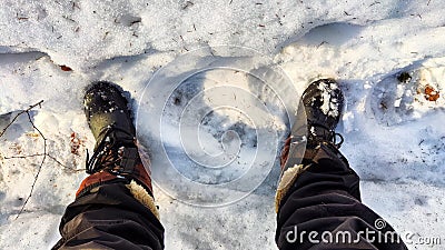Feet of Hunter or fisherman in big warm boots on a winter day on snow. Top view. A fisherman on the ice of a river, lake Stock Photo