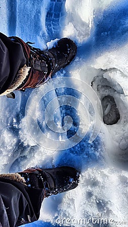 Feet of Hunter or fisherman in big warm boots on a winter day on snow. Top view. A fisherman on the ice of a river, lake Stock Photo