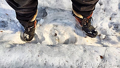 Feet of Hunter or fisherman in big warm boots on a winter day on snow. Top view. A fisherman on the ice of a river, lake Stock Photo