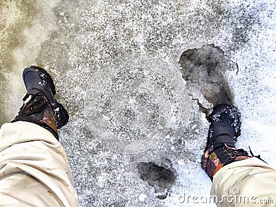 Feet of Hunter or fisherman in big warm boots on a winter day on snow. Top view. Fisherman on the ice of a river, lake Stock Photo