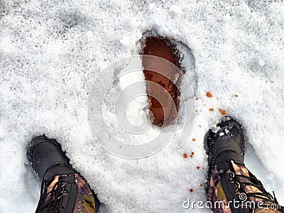 Feet of Hunter or fisherman in big warm boots on a winter day on snow. Top view. Fisherman on the ice of a river, lake Stock Photo