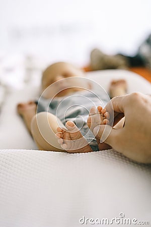 The feet of the newborn lying in Baby Cocoon and fathers hands gently touch, doing a gentle massage. Stock Photo