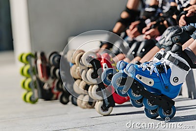 Feet of rollerbladers wearing inline roller skates sitting in outdoor skate park, Close up view of wheels befor skating Stock Photo