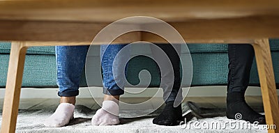 Feet sticking out under a sofa table Stock Photo