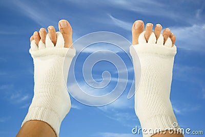 Feet with yoga toe separator socks on sky background Stock Photo