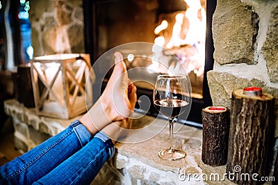 Feet of unrecognizable woman in front of the fireplace. Stock Photo