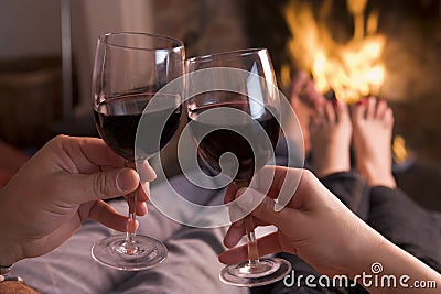 Feet warming at fireplace with hands holding wine Stock Photo